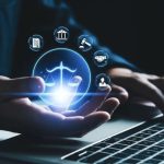 تجسيد إلغاء الدفع بالاختصاص المكاني وتوحيد النطاق القضائي داخل المملكة عبر منصات عدلية رقمية: يدّان تحملان رمز ميزان القانون فوق لوحة مفاتيح.